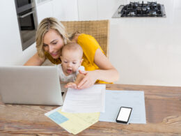 Mother using laptop with baby boy in kitchen at home